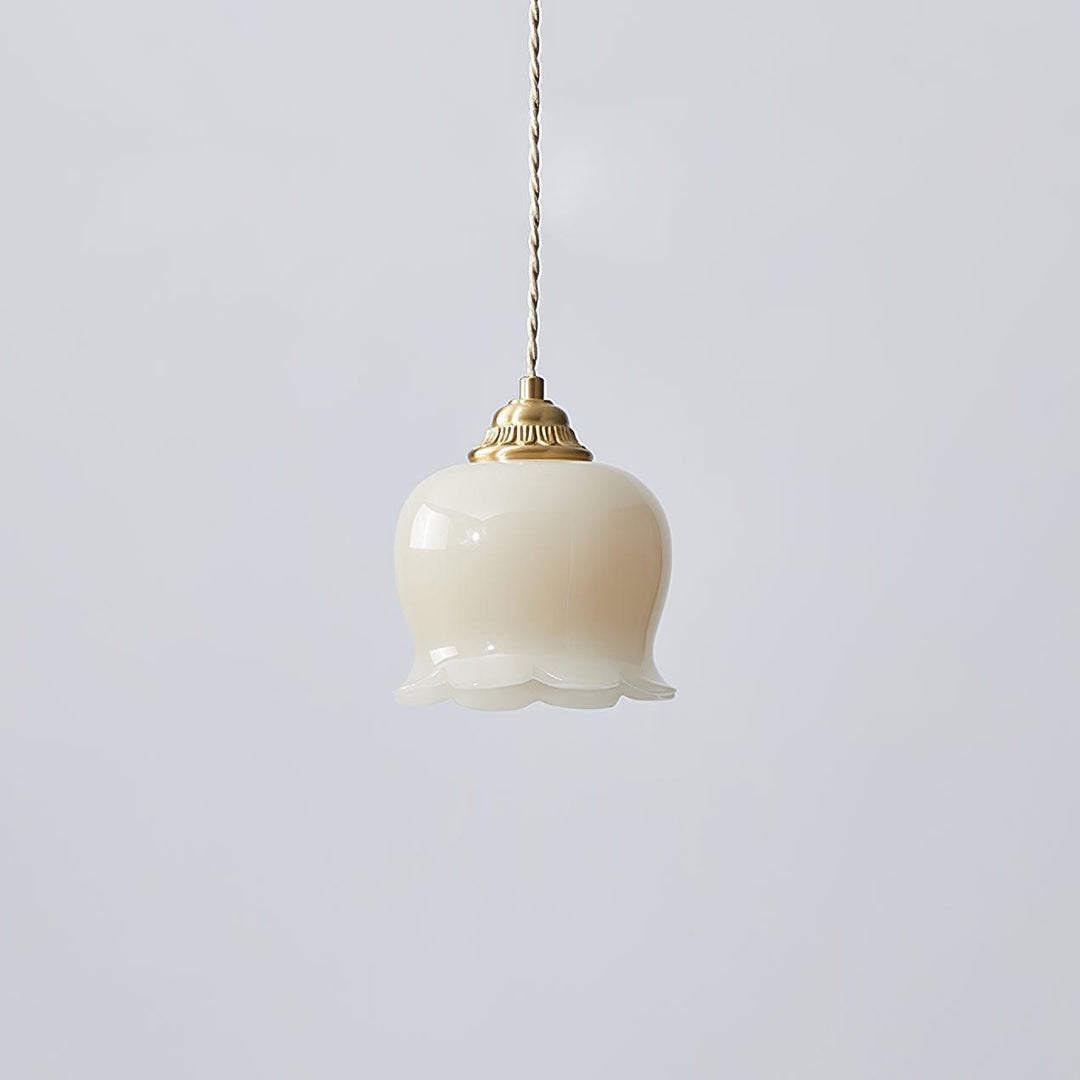 Brass and beige flower pendant light with a smooth resin shade and twisted cord, shown unlit