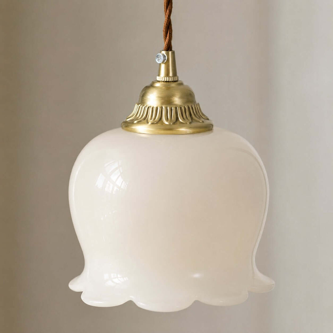 Close-up of the brushed brass cap, twisted cord, and scalloped resin shade on the flower pendant light