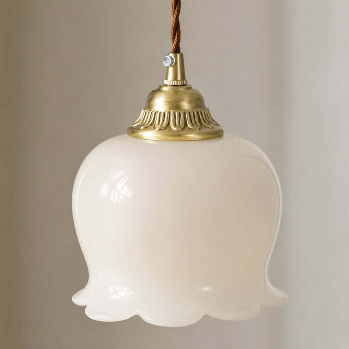 Close-up of the brushed brass cap, twisted cord, and scalloped resin shade on the flower pendant light