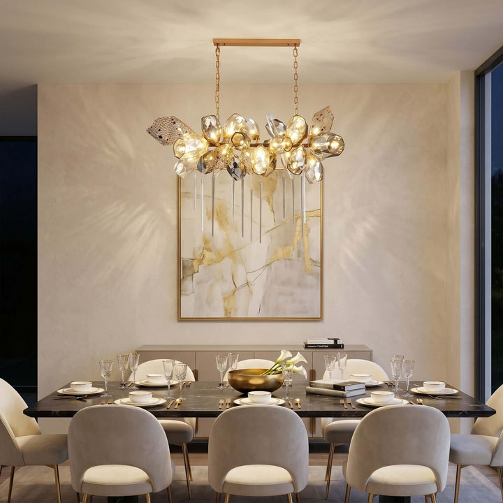 Horizontal Britannica dining room chandelier glowing above a large table in a modern neutral interior.