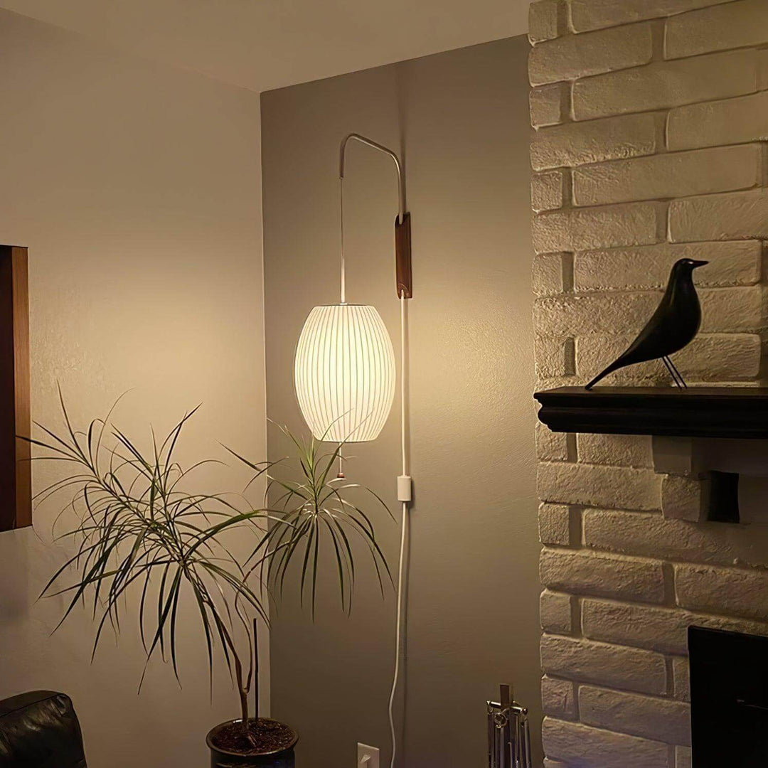 Oval Bubble Ball wall sconce lighting a living room corner beside a plant and brick fireplace
