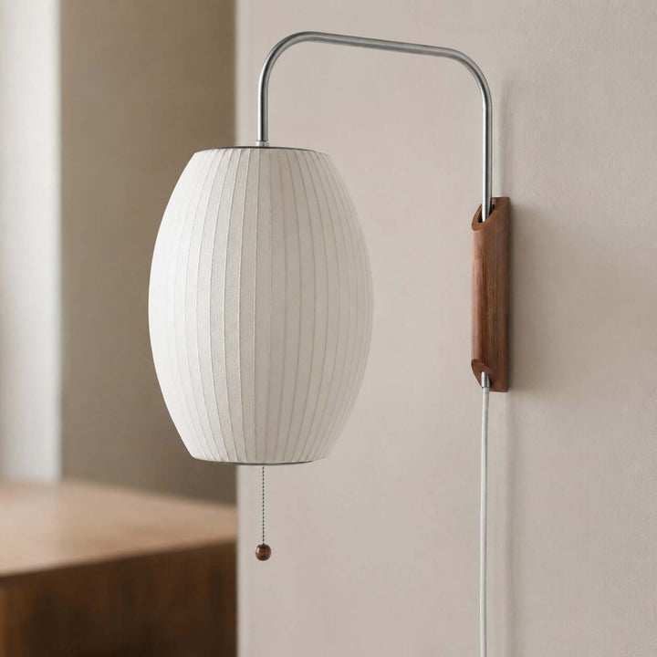 Close view of the oval Bubble Ball wall sconce with a ribbed white shade and walnut mount