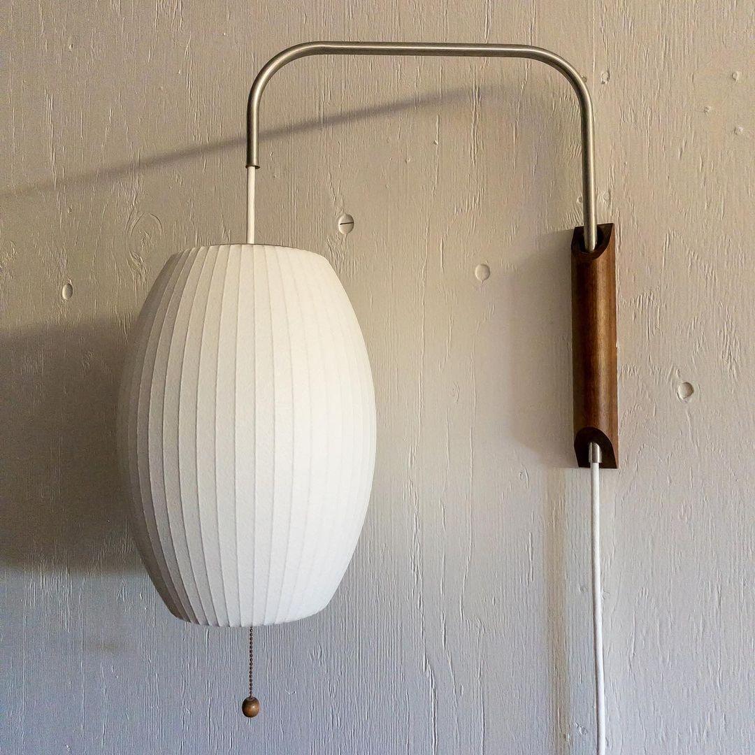 Unlit Bubble Ball wall sconce showing its oval ribbed shade, curved arm, and walnut base