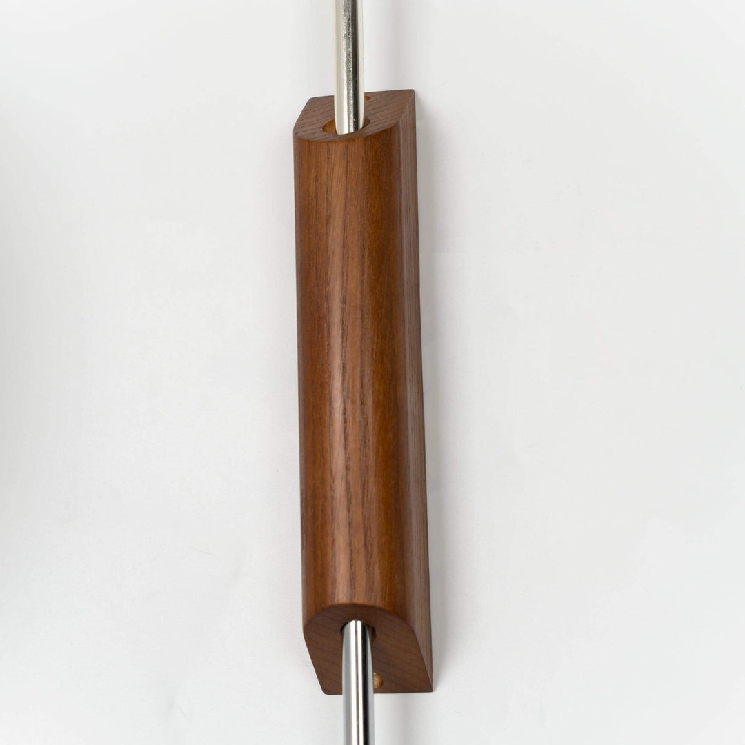 Close-up of the Bubble Ball wall sconce walnut mounting base and polished metal arm