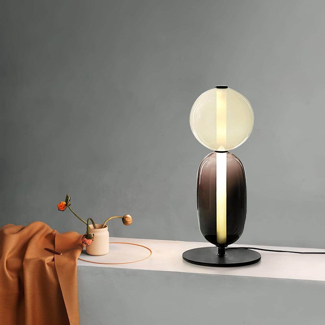 Collection of colorful stacked glass table lamps and pendant lights glowing in multiple shapes