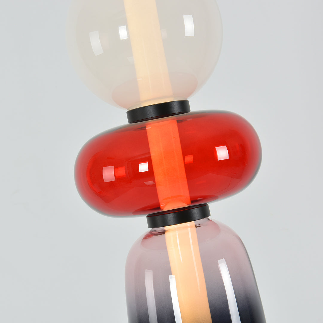 Close-up of the glossy red oval glass accent and illuminated center of the Candied floor lamp.