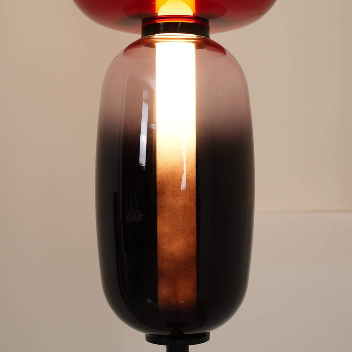 Close-up of warm light shining through the tall smoky glass shade of the Candied floor lamp.