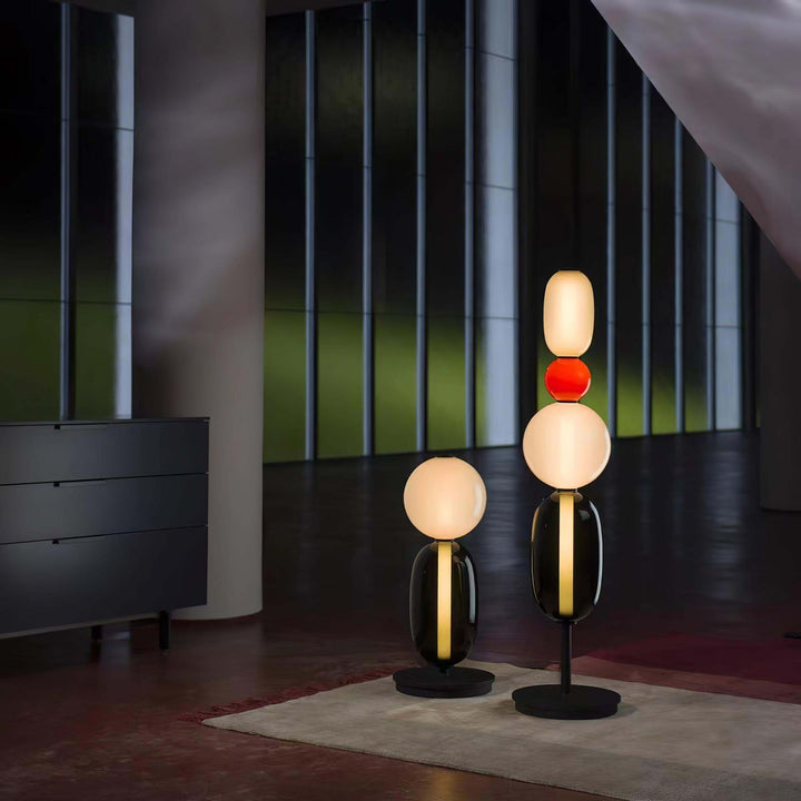 Tall Candied glass floor lamp and shorter table lamp glowing together in a dark contemporary interior.