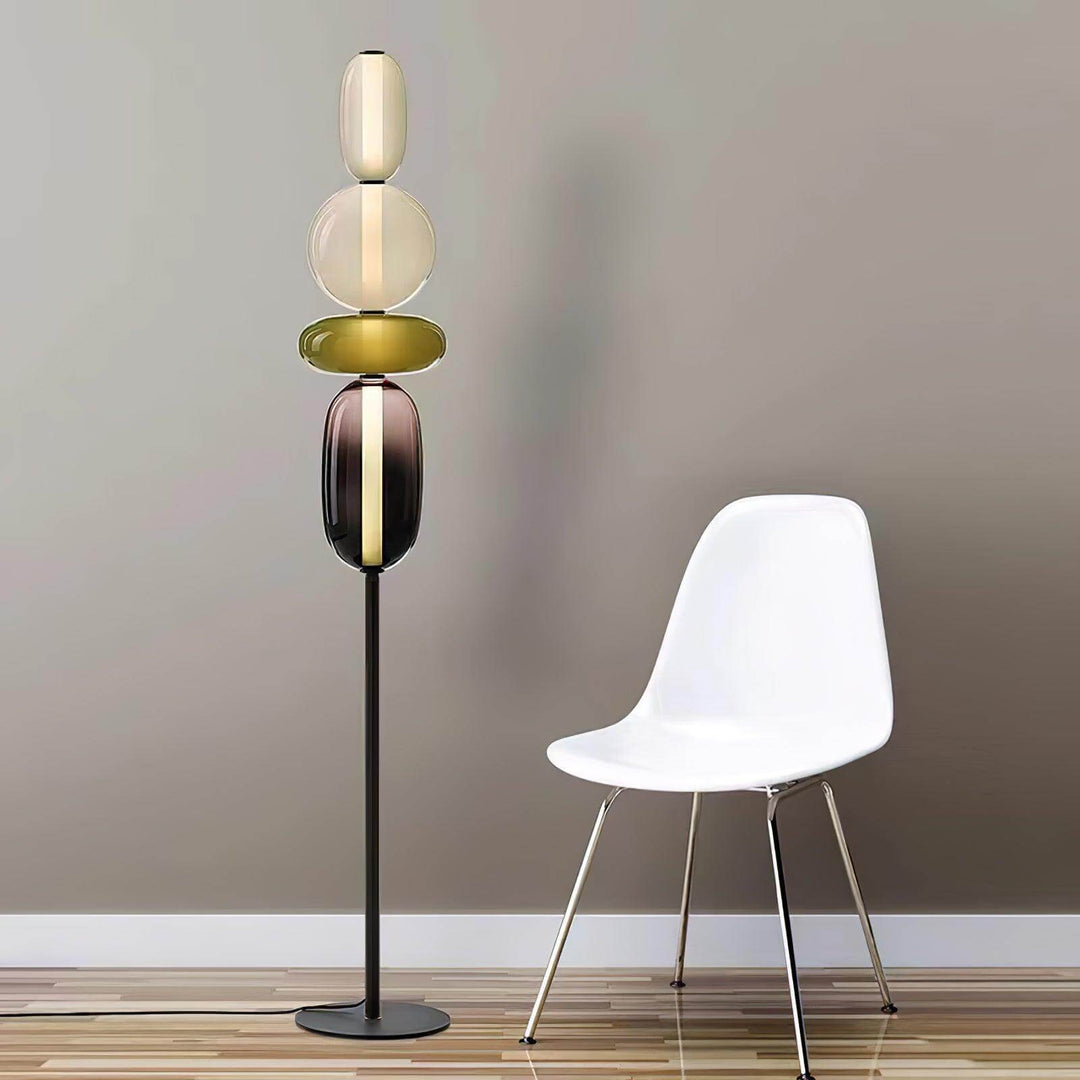 Candied green glass floor lamp beside a modern white chair on a striped wood floor.