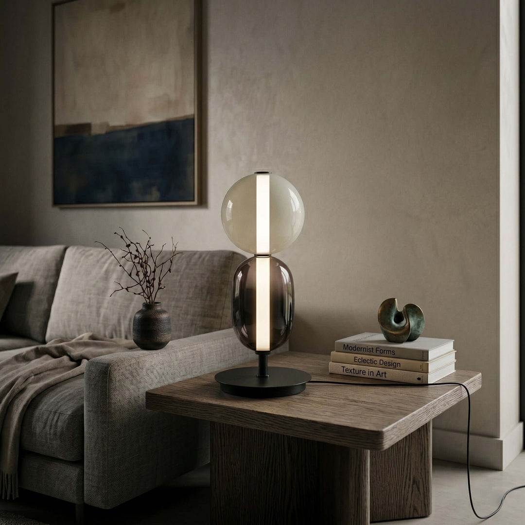 Modern glass table lamp with clear globe and smoked oval body on a living room side table