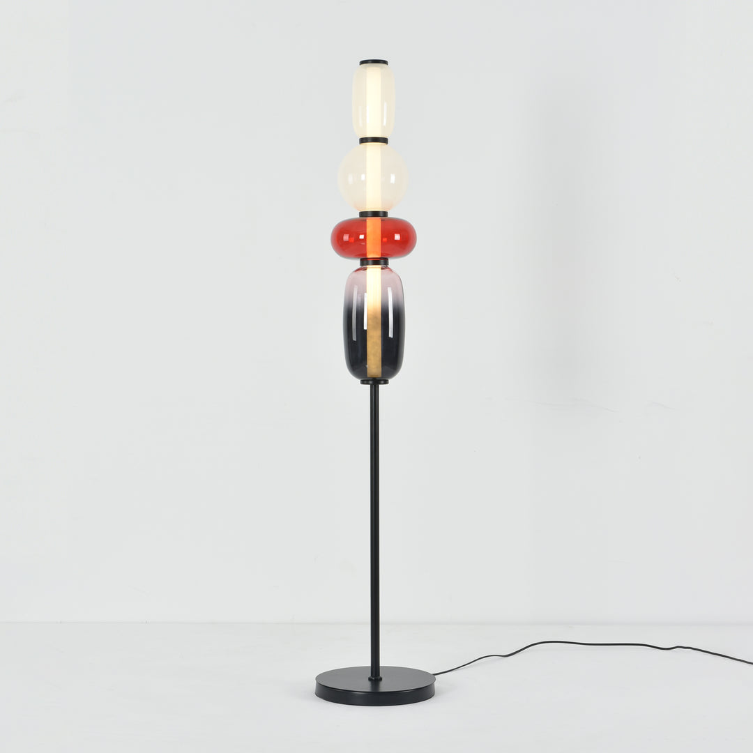 Illuminated Candied Model A Red glass floor lamp with a slim black stem and round base on a white background.