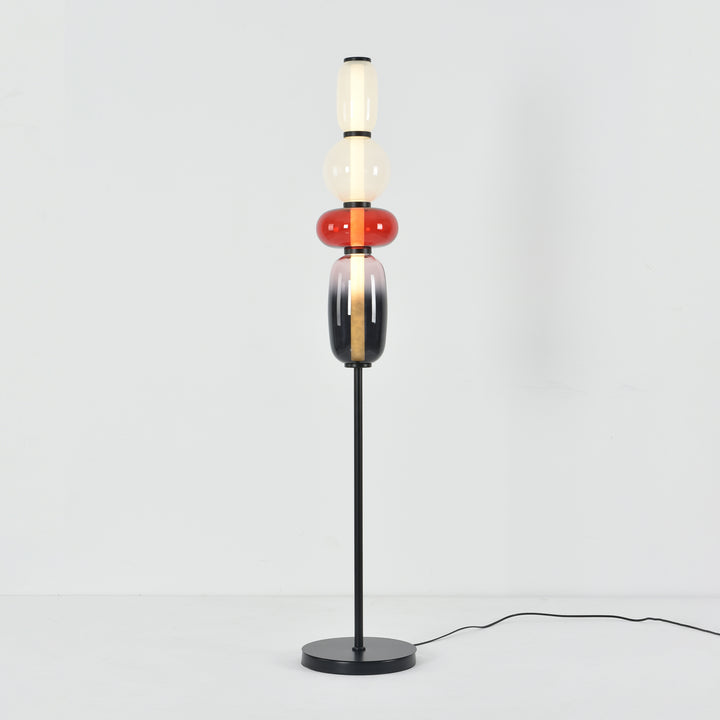 Illuminated Candied Model A Red glass floor lamp with a slim black stem and round base on a white background.