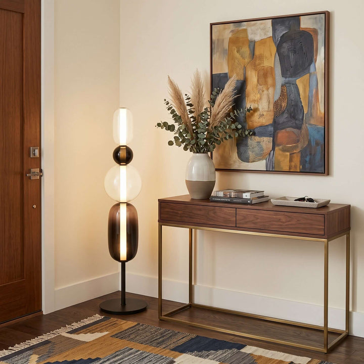 Candied Model B Black floor lamp beside a walnut console and colorful abstract art in an entryway.