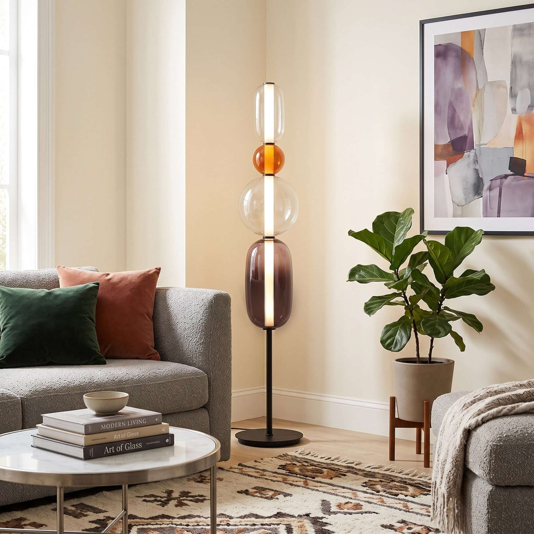 Candied Model B Orange floor lamp with stacked clear and smoky glass beside a gray sofa and potted plant.