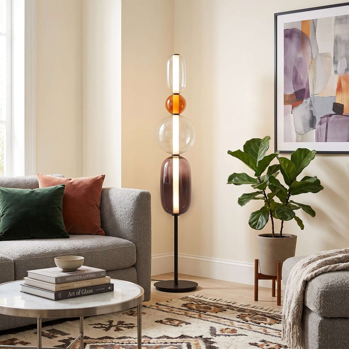 Candied Model B Orange floor lamp with stacked clear and smoky glass beside a gray sofa and potted plant.