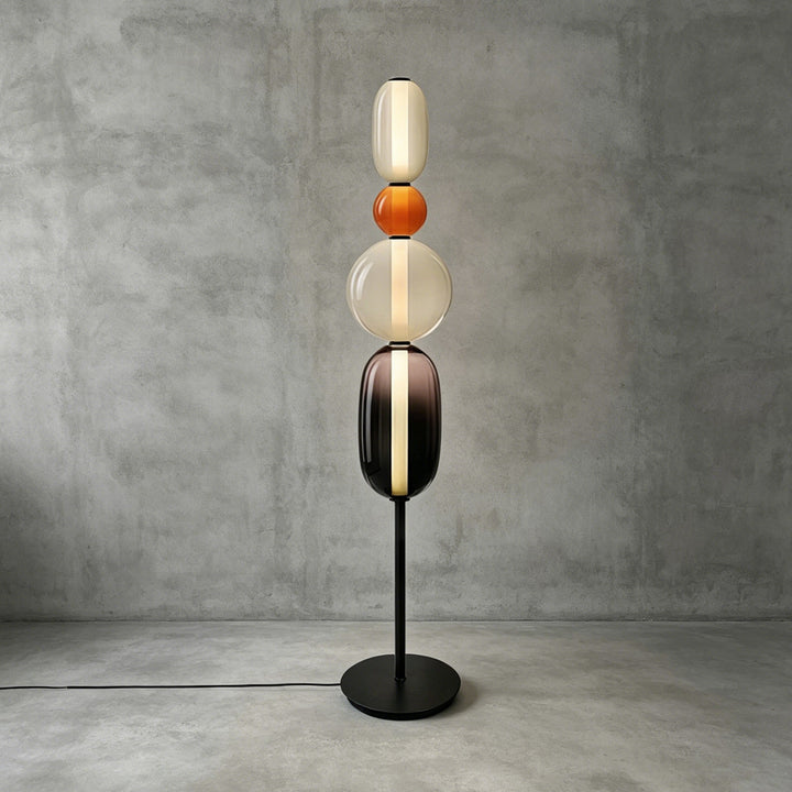 Tall Candied Model B Orange glass floor lamp with a warm vertical light and round black base.