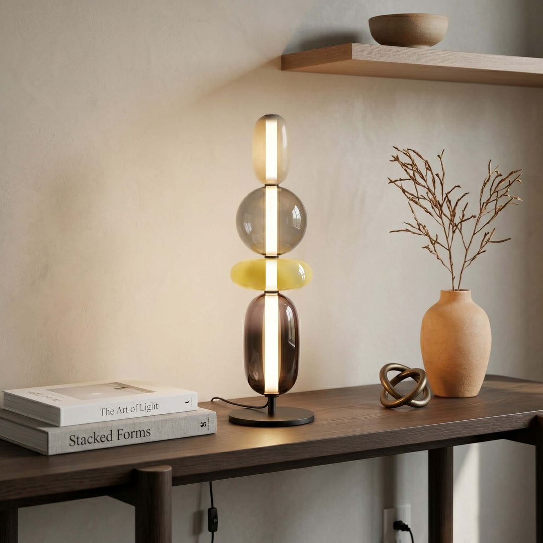 Tall art deco glass table lamp with stacked clear, green and smoked forms on a console table