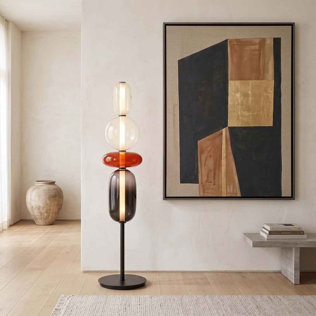 Candied red glass floor lamp glowing beneath large black and gold abstract wall art.