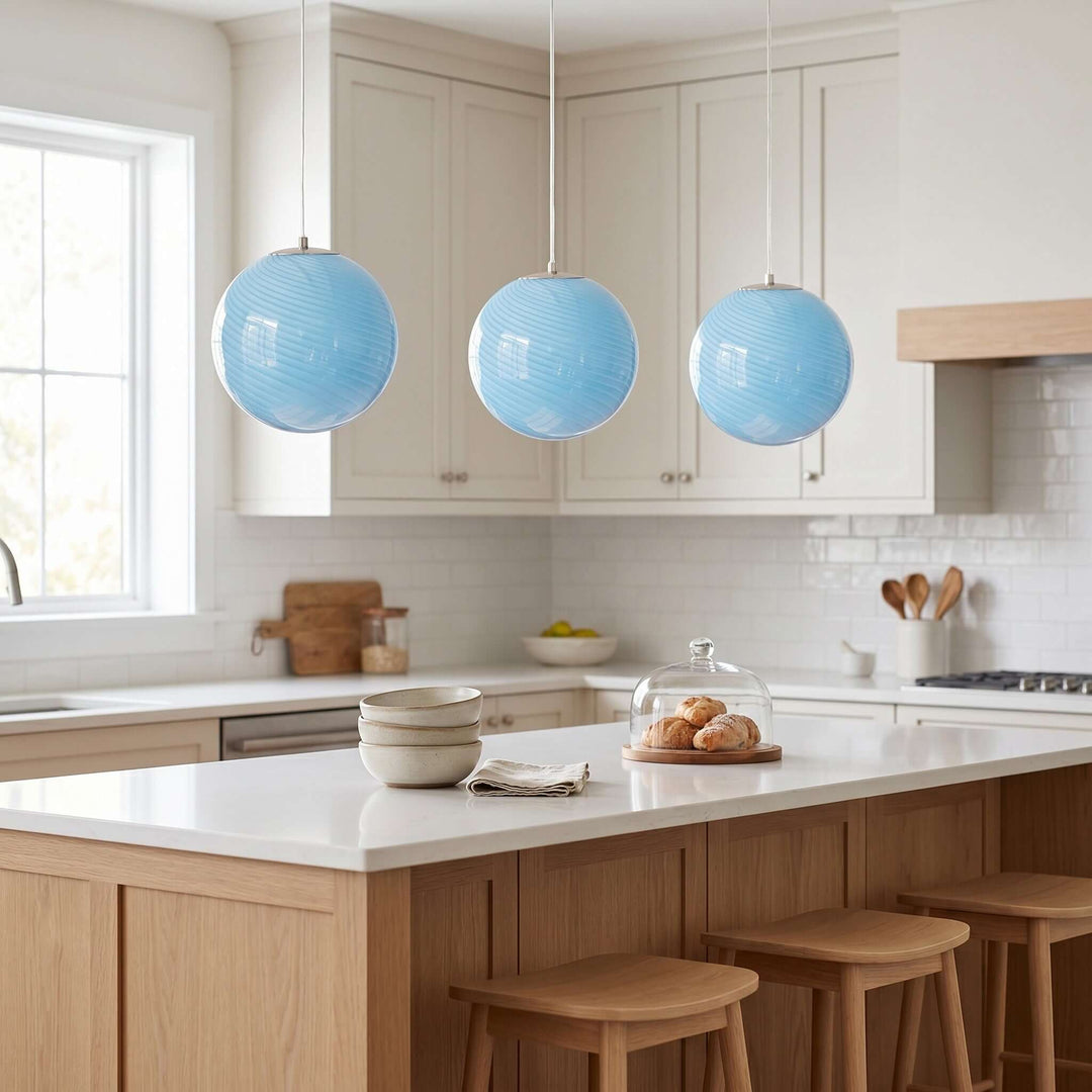Three light blue Candy glass pendant lights hanging over a white kitchen island.