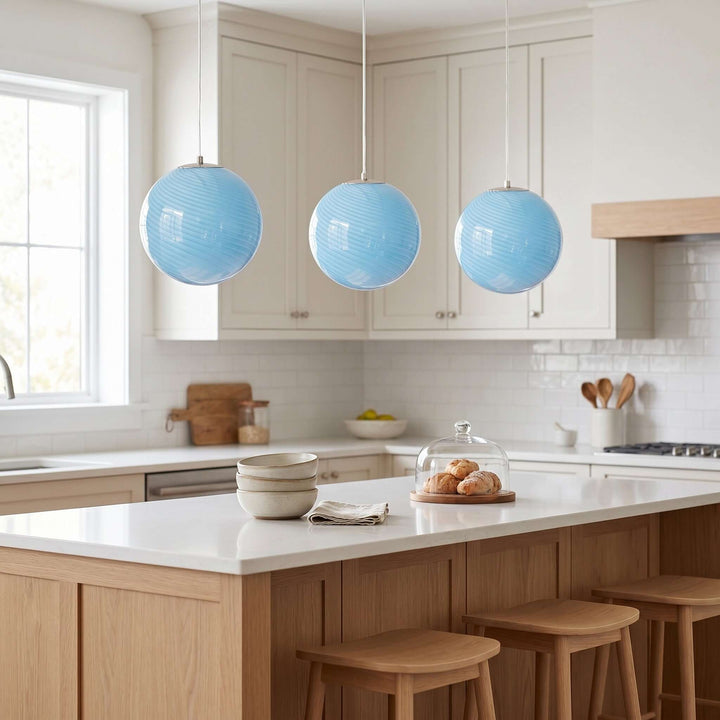 Three light blue Candy glass pendant lights hanging over a white kitchen island.