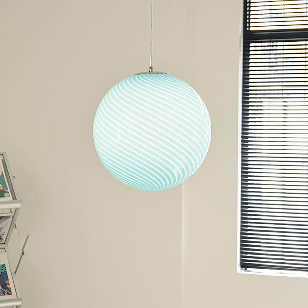 Illuminated light blue Candy ribbed glass pendant light hanging beside a window.