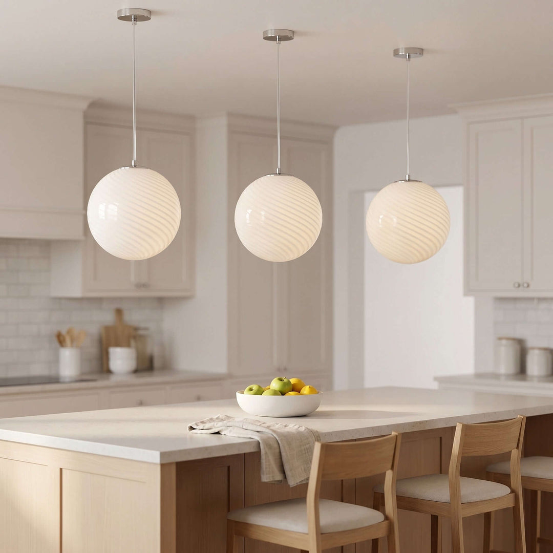 Three white Candy glass pendant lights over a large kitchen island in a warm modern kitchen.