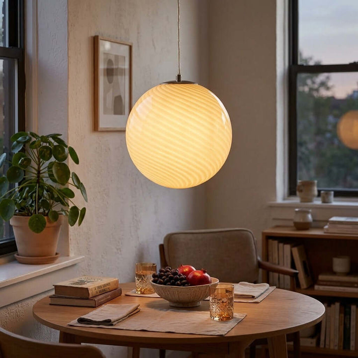 Illuminated yellow Candy Glass Pendant Light above a round dining table at dusk.