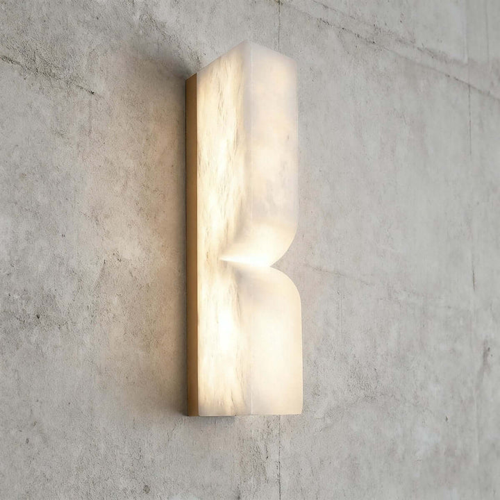 Cavira 13.8-inch alabaster wall sconce illuminated on a textured wall with a warm diffused glow