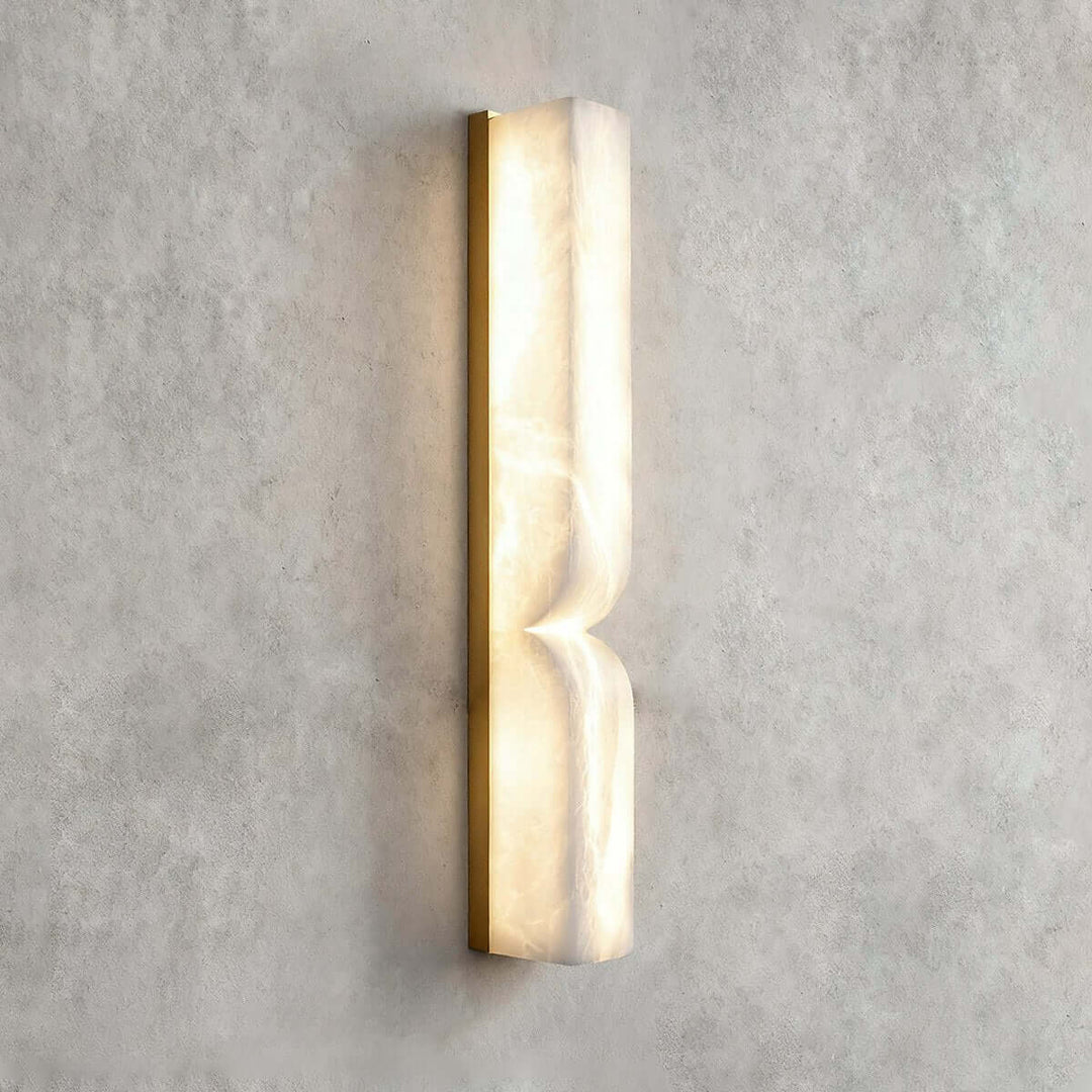 Cavira 23.6-inch alabaster wall sconce illuminated on a textured wall with a tall sculptural profile