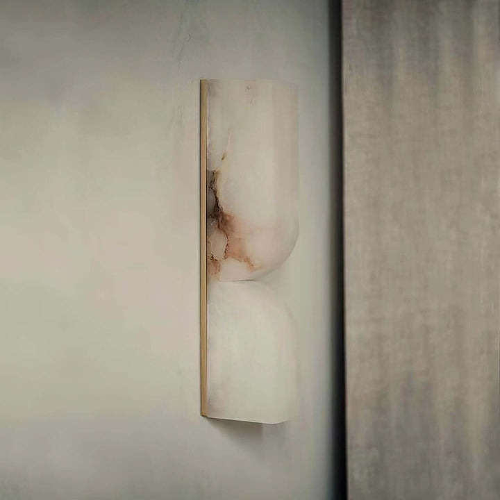Unlit Cavira Wall Sconce shown from the side with pale alabaster, dark natural veining and a slim metal frame
