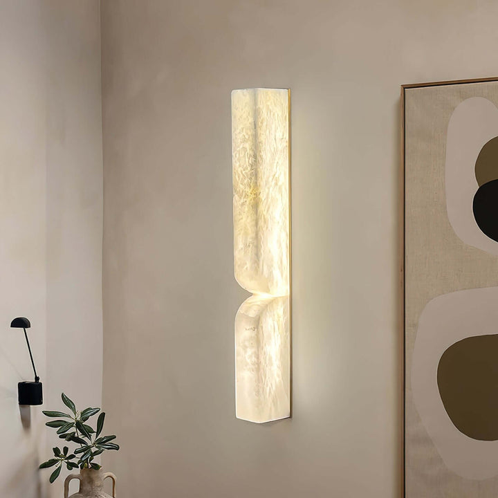 Tall Cavira alabaster wall sconce displayed in a minimalist interior beside large abstract artwork