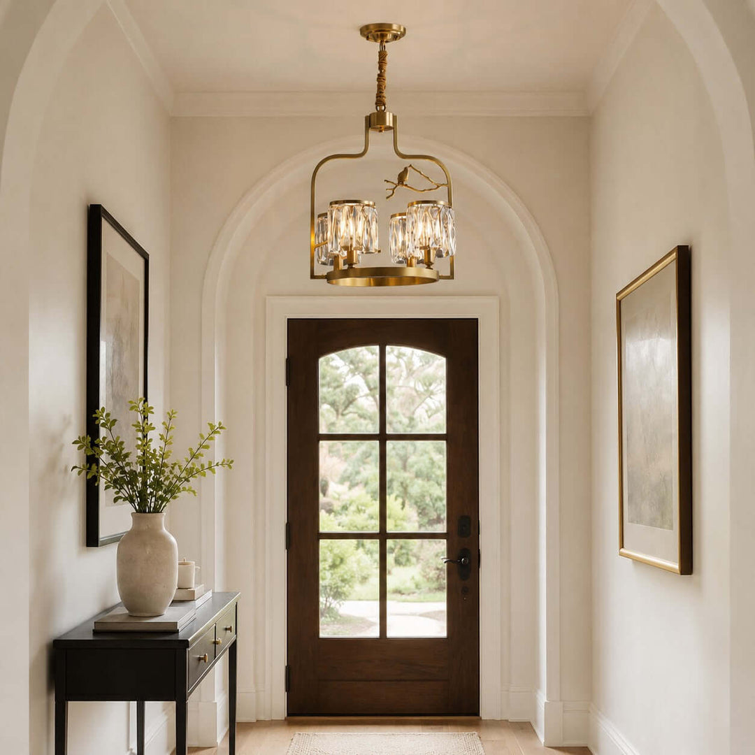 Brass and crystal chandelier with bird details hanging in an arched entryway above a wood front door
