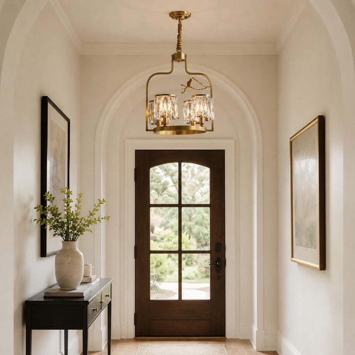 Brass and crystal chandelier with bird details hanging in an arched entryway above a wood front door
