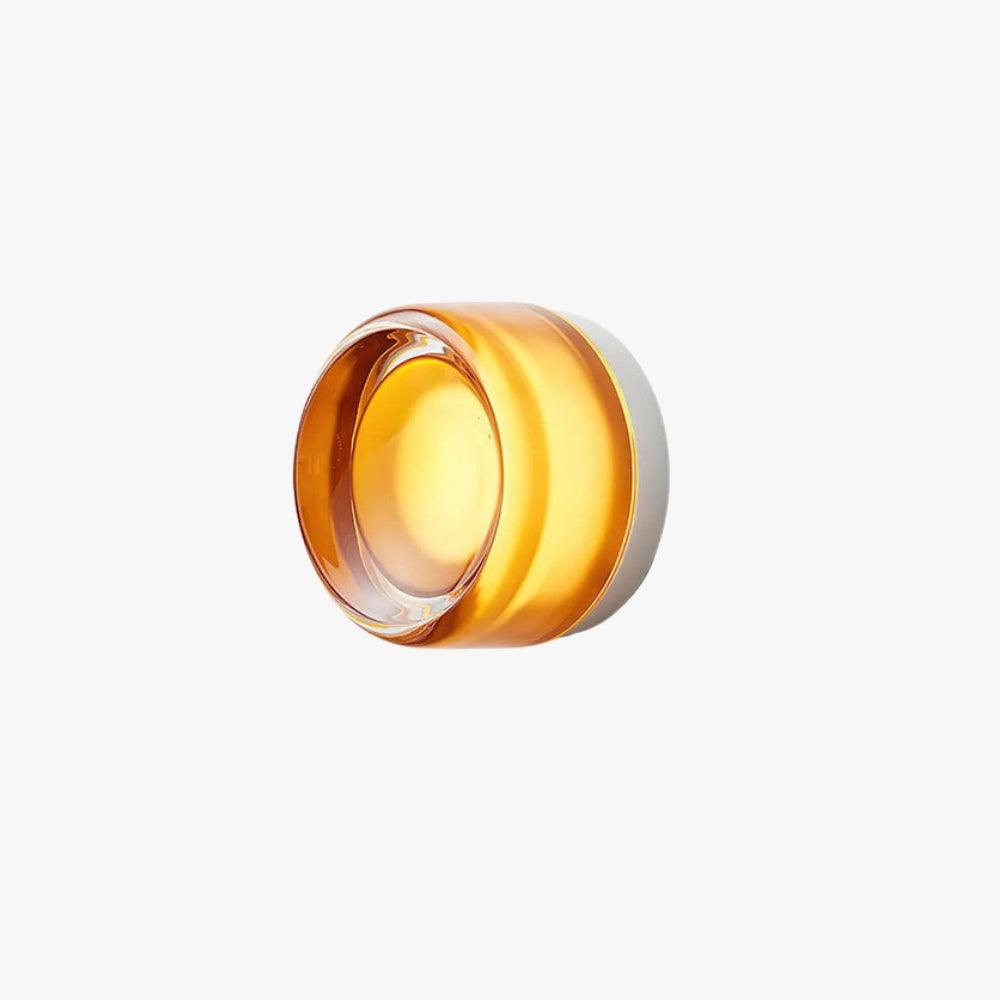 Amber glass wall sconce lit on a white background with a round clear lens.