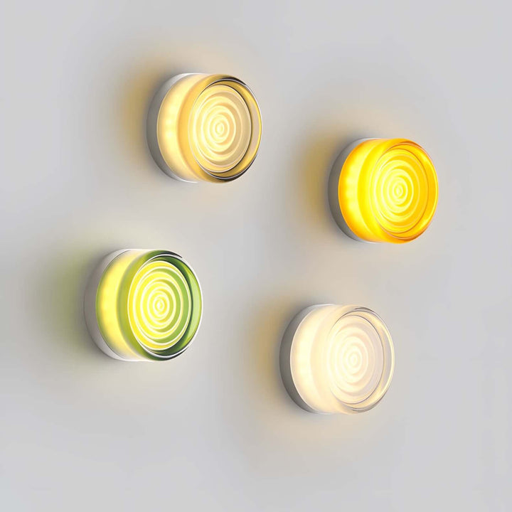 Four lit concentric glass wall sconces showing multiple color options.