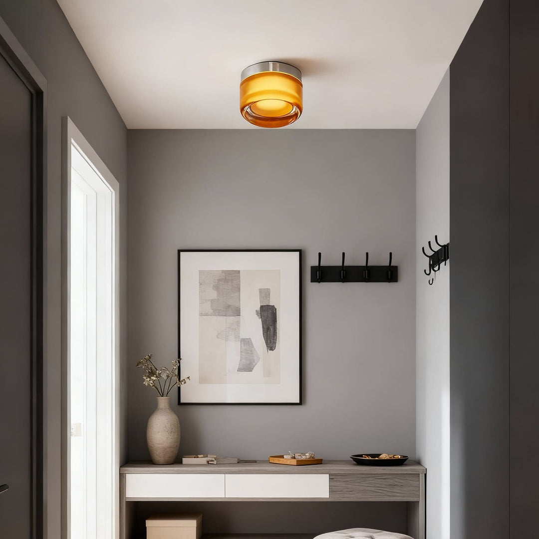 Amber glass ceiling-mounted light in a gray entry hall with hooks and framed art.