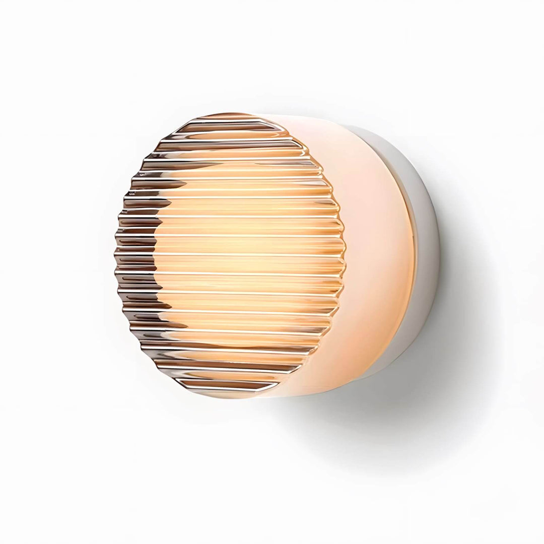 Ribbed amber glass wall sconce lit on a white background with a textured round front.