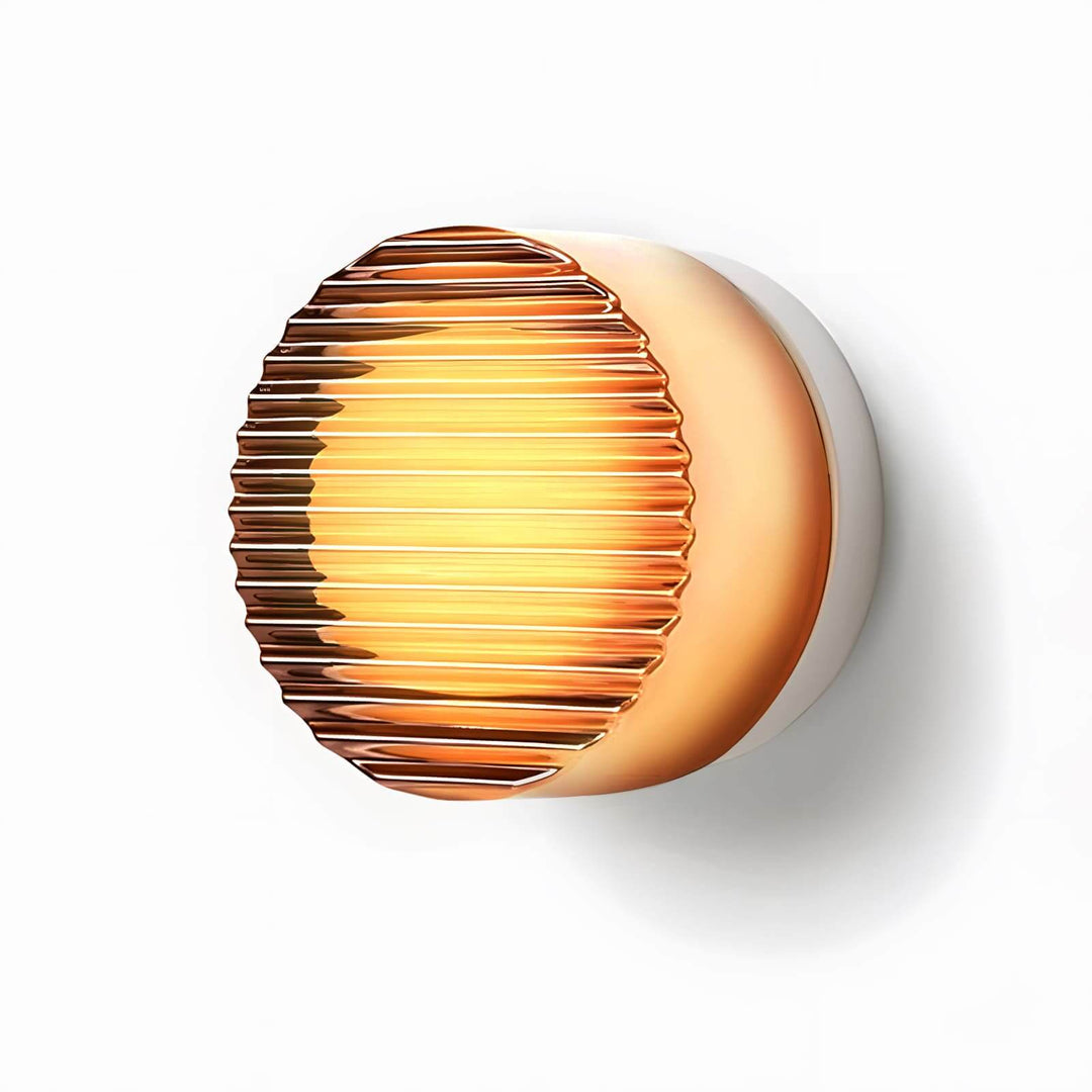 Bright amber ribbed glass wall sconce with warm glow and round textured front on white.