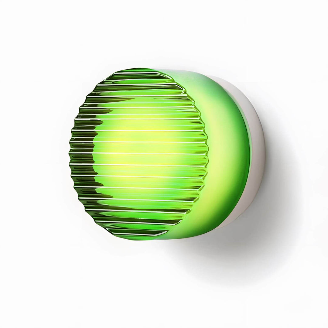 Green ribbed glass wall sconce with a warm center glow and round textured front.