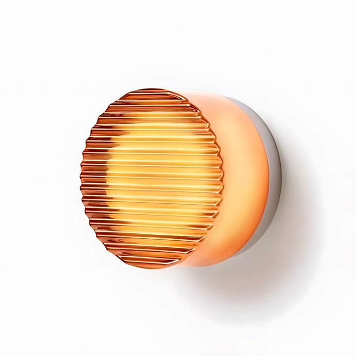 Amber ribbed glass wall sconce with textured front detail and warm light on a white background.