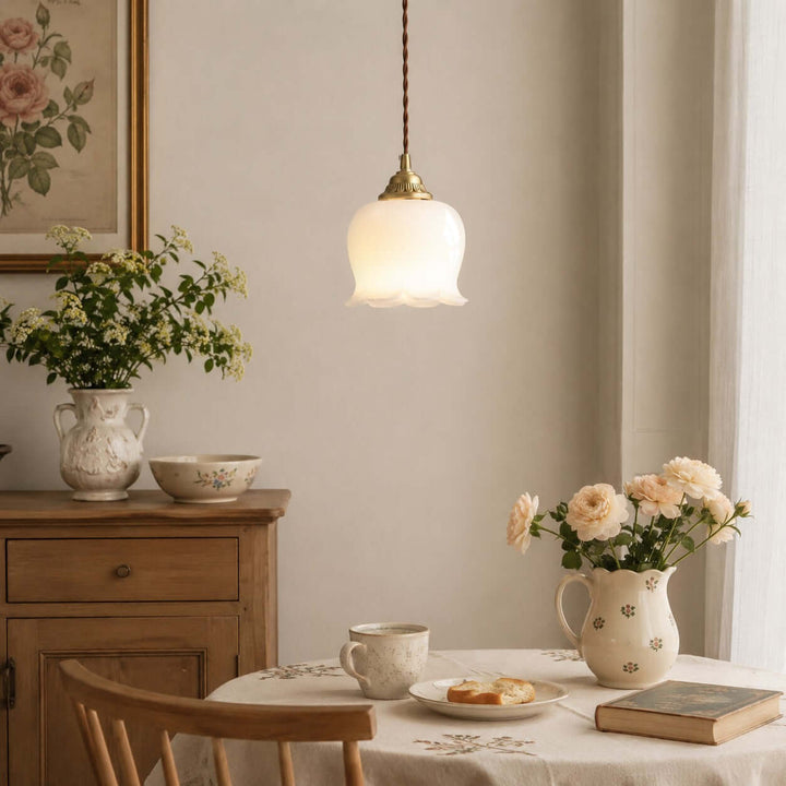 Warm dining hanging light with a flower-shaped resin shade above a table styled with floral decor