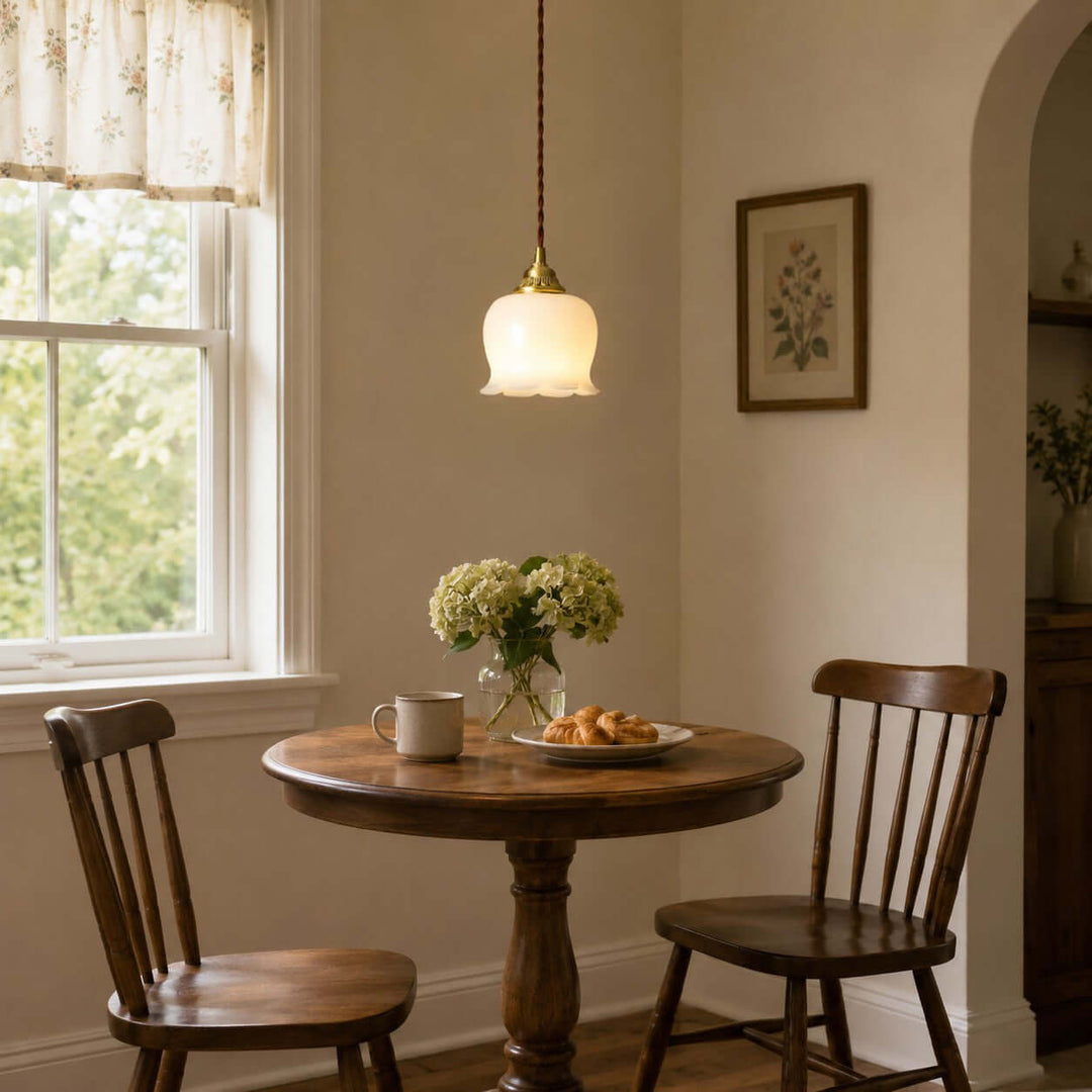Brass flower pendant light illuminating a small wooden dining table in a warm vintage dining nook