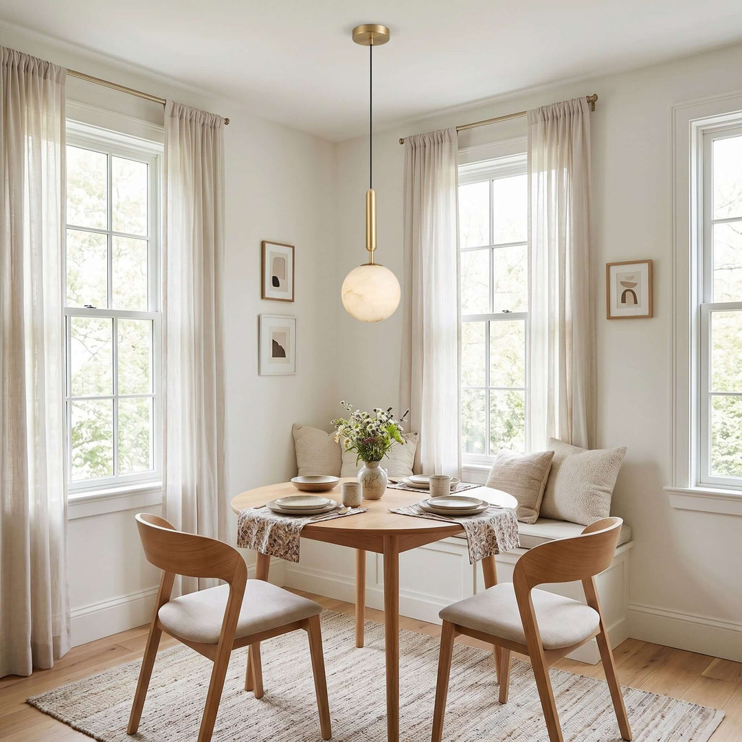 Small alabaster globe pendant light above a round dining table in a bright breakfast nook