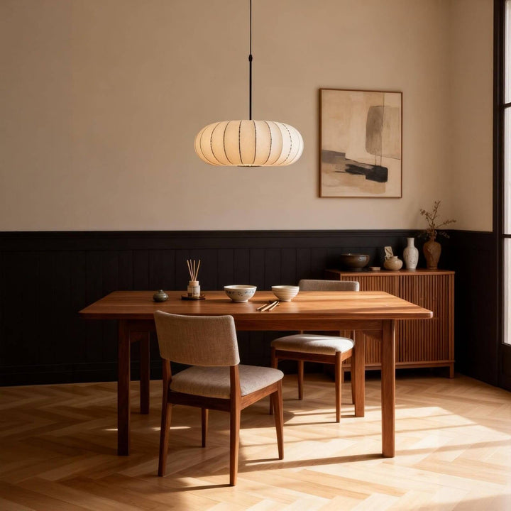 White oval silk pendant light centered over a mid-century wooden dining table