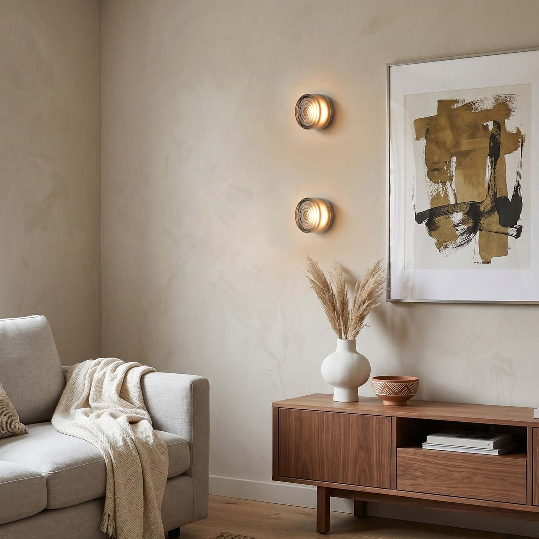 Two Dimple wall sconces stacked above a living room cabinet.