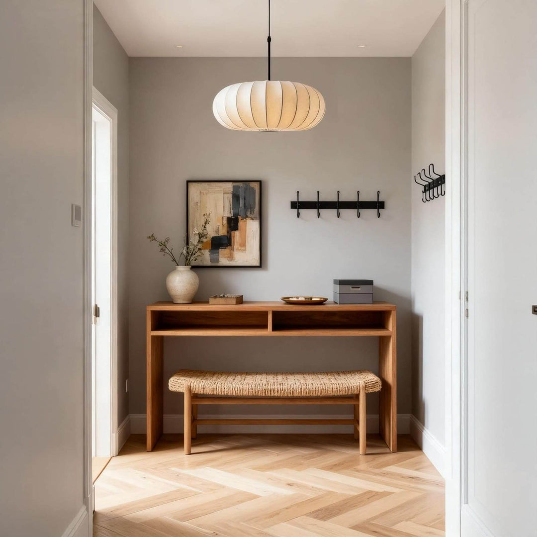 Round white pendant light above a console table and woven bench in an entryway