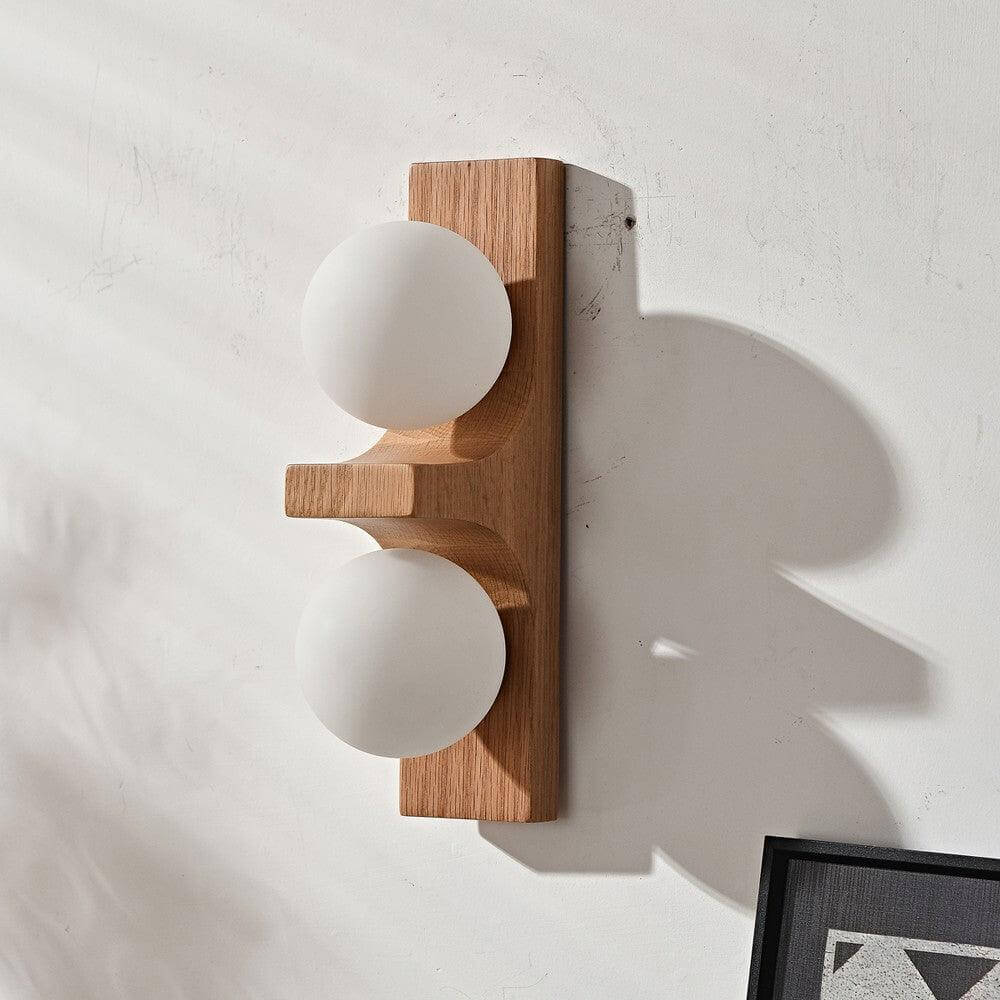 Light wood double wall sconce with two white glass globes on a textured wall with soft shadow