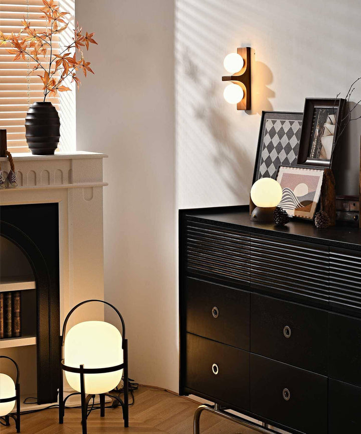 Wood double wall sconce glowing in a living room corner with fireplace black cabinet and floor lamps