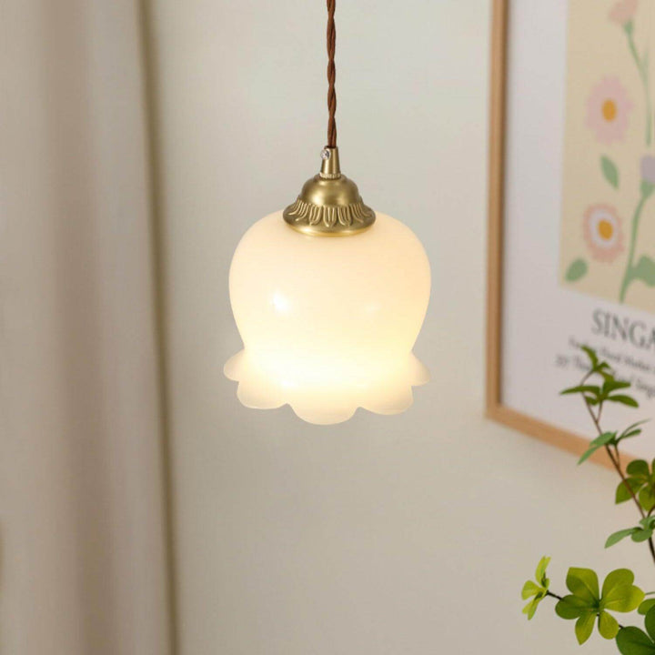 Close view of a glowing flower pendant light with a scalloped resin shade and vintage brass accents