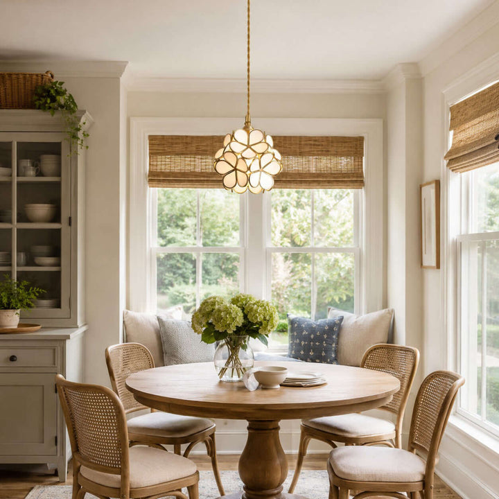 White glass petal pendant light above a round wood dining table in a bright breakfast nook